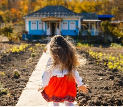 A young girl in a red skirt running towards a house